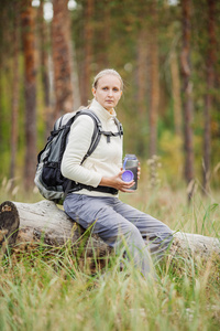 用背包在森林山谷的年轻女人喝水