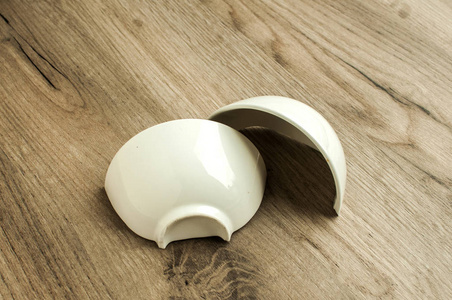 碎在二半小白色瓷碗特写在木板背景上照片