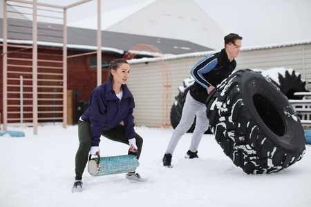 年轻运动妇女和人训练与重的轮胎, 室外