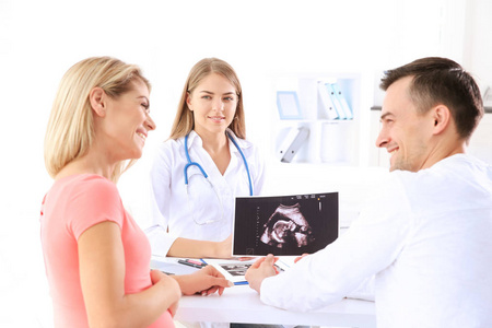 妇科会诊。医生显示超声扫描婴儿对夫妇