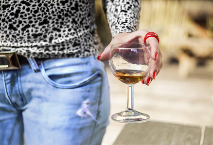 女性的手与红色长钉子拿着葡萄酒杯