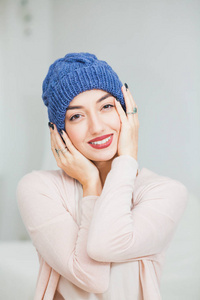 年轻的妇女在温暖的深蓝手针织帽子在家。漂亮的女士在蓝色的帽子, 愉快地微笑着。垂直射击