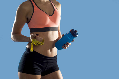 体育女人拿着矿泉水瓶和措施磁带显示苗条完美 abs 和胃