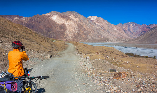 站在山区道路上的年轻车手。印度北部喜马拉雅山，查谟和克什米尔邦