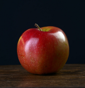 熟透的红苹果，一个黑色的背景上深色木制的桌子上
