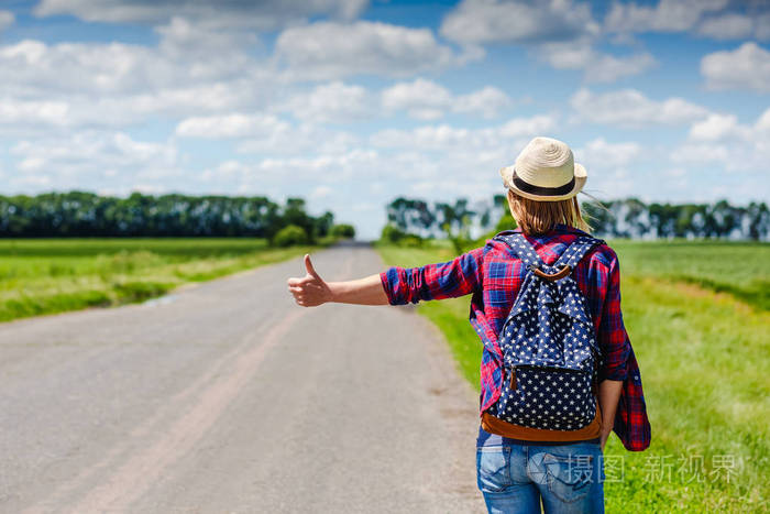 帽子和背包在路上搭车的女孩