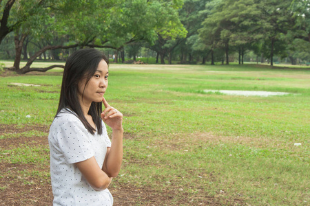 女人穿着白色的 t恤, 站在公园的绿草, 她想的东西