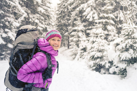 幸福的女人走在冬季森林与背包