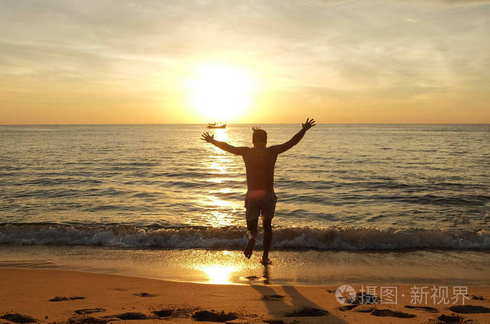 快乐的人在海滩奔跑到海在日落