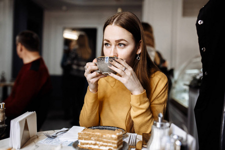 喝咖啡的美丽的年轻妇女坐在桌在咖啡馆