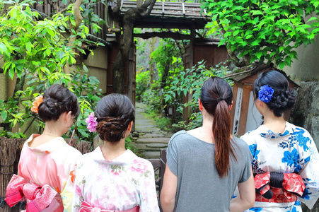 三日本年轻女子身穿夏季 yukatas 和欧洲女性游客步行一起通过日本典型的花园入口靠近世界遗产清水寺在京都, 日本