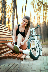 rts 女孩在顶部和短裤领带在一个公园的日落长凳上的运动鞋鞋带