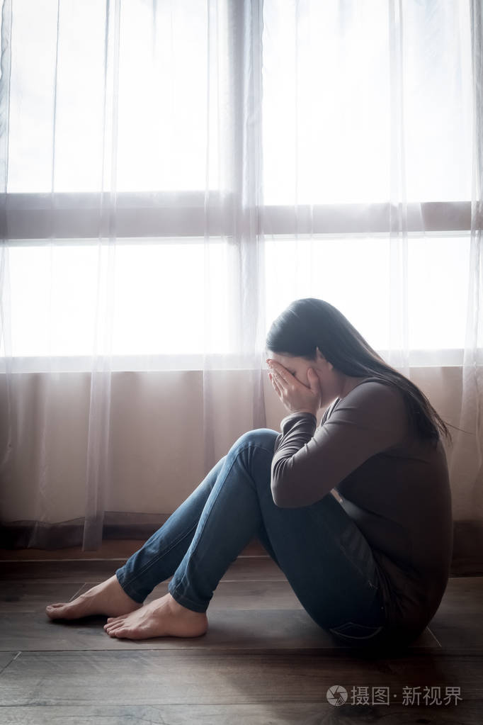 郁闷的女人坐在地板上的房间里