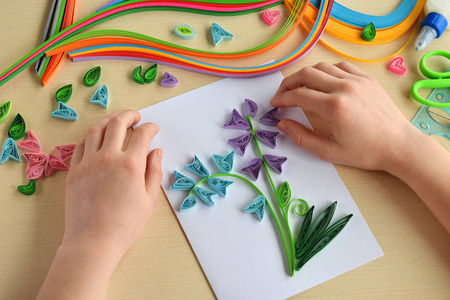 Quilling 技术。制作装饰品或贺卡。纸条, 花, 剪刀。手工工艺品在假日 生日, 母亲或父亲的天, 3月8日, 婚礼。儿