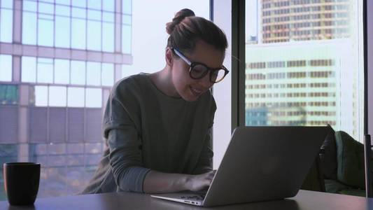 笔记本电脑键盘上的眼镜时髦眼镜的商界女性开始在笔记本电脑上工作.