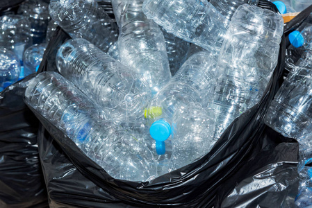 在黑色的垃圾袋里等待被采取回收塑料瓶