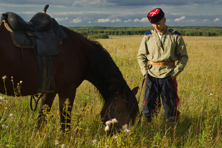 俄罗斯哥萨克与一匹马在夏天场休息