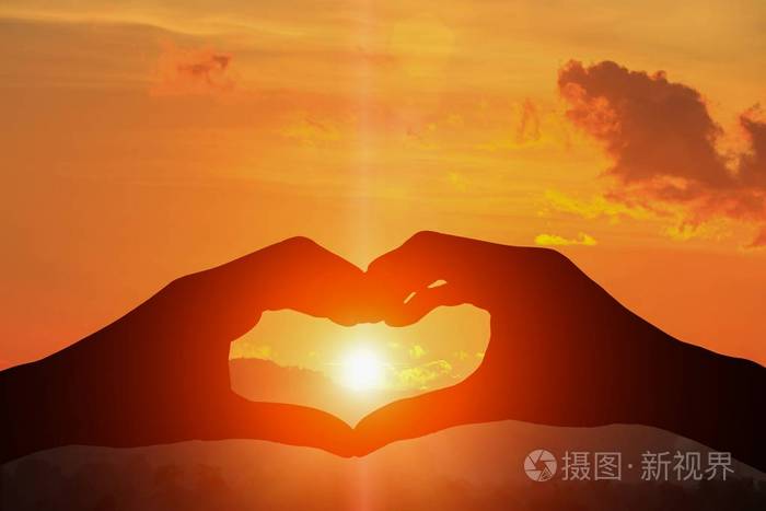 手形成剪影一个心脏形状与日落光