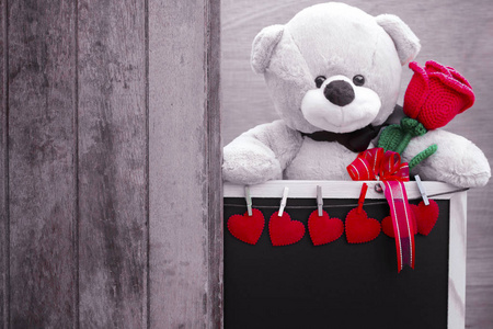 可爱的泰迪熊玩具紧握着红色的玫瑰在它的胳膊和 blackbo