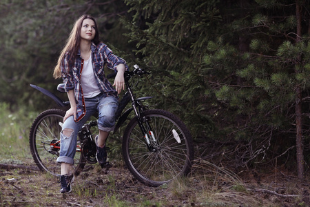 年轻女孩夏季森林体育自行车
