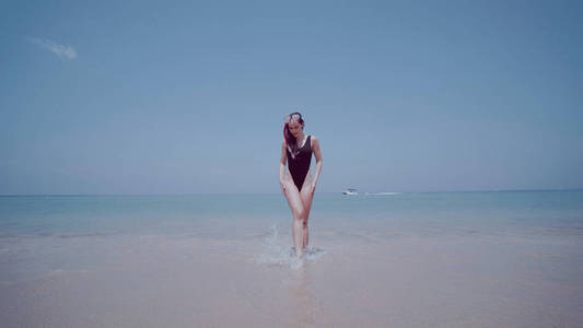 美丽的年轻女子泳装与浮潜面具有乐趣在海水上空的蓝天背景。美丽的女孩享受阳光明媚的夏日在她的海滩热带假日