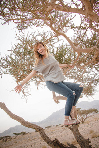 美丽的女孩在沙漠中的树上玩得开心