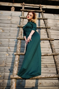 永安优雅的金发女孩在绿色的裙子背景木制楼梯
