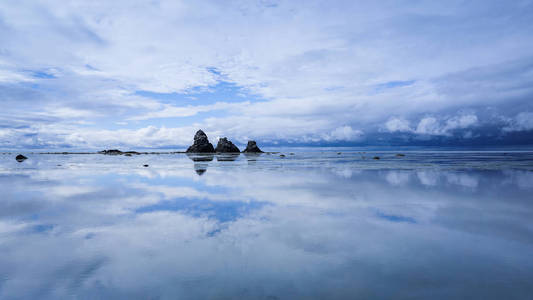 平静海水中的天空岩石和云彩的倒影