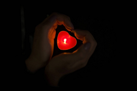 心形手捧着一支蜡烛在黑暗中照片