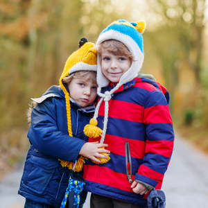 在寒冷的冬日拥抱的两个有趣小小孩同级男孩