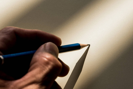 人的手拿着铅笔写在纸上的阴影