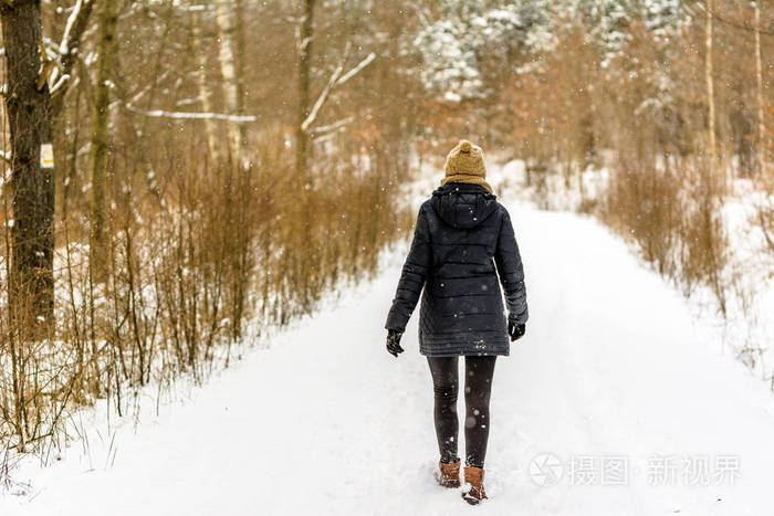 穿着冬衣的女孩在雪地里散步.森林里雪路上的女人