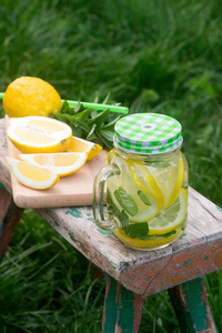 自制柠檬水与薄荷和冰在一个木凳在花园里。乡村风格