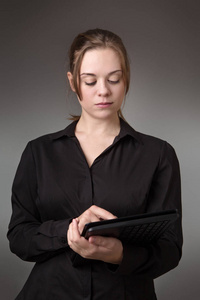年轻的商业妇女使用电脑拍摄在工作室的灰色背景