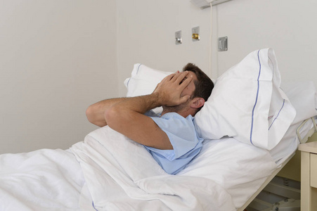 年轻有耐心的人躺在医院的床上休息累了看难过和沮丧，担心