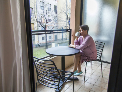 墙纸美女睡衣穿着粉红色睡衣的年轻美女在多云的早晨在阳台上喝咖啡.