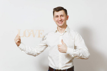 年轻的微笑的男子在衬衫上显示拇指高举木字的爱情孤立在白色的背景。广告的复制空间。St. 情人节, 国际妇女节的生日假期概念