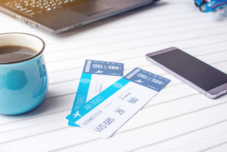 杯咖啡飞机票, 电话和笔记本电脑上白色的木质背景。购买网上订票的概念