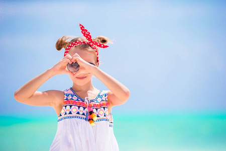 加勒比海度假时在海滩上的小女孩。美丽的孩子的肖像背景蓝天