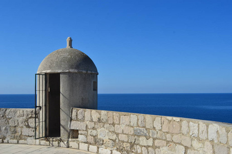 在杜布罗夫尼克的石墙上俯瞰大海的一座守卫塔。海是蓝的, 天空也一样。场面是冷清的
