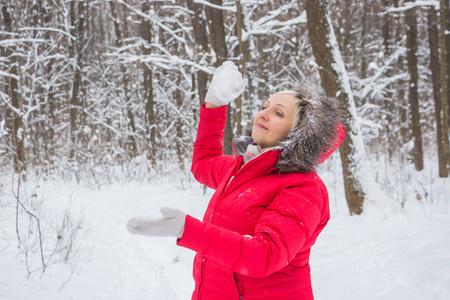 老妇人用红大衣把雪球扔在木头上。