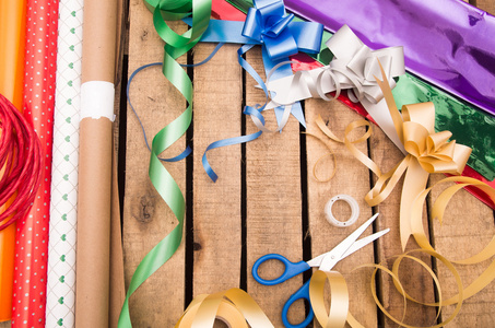 礼品包装概念与各种纸张颜色, 剪刀, 胶带和其他装饰躺在木制表面