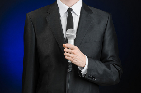 主题演讲商务和演讲主题:穿黑色西装的男人拿着一个微型面罩照片