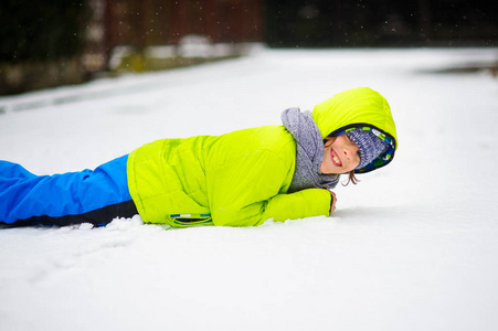 学龄儿童的开朗的男孩躺在雪上图片