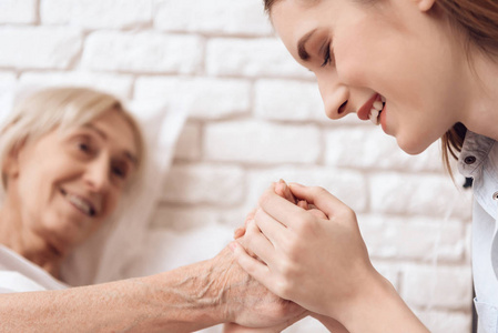 女孩照顾老人在床上的家庭和他们牵手