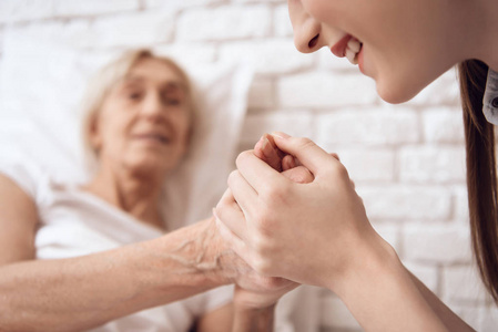 女孩照顾老人在床上的家庭和他们牵手