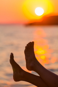 夕阳下的海岸上的粗心脚