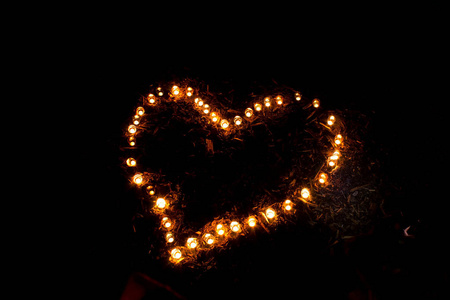 燃烧的蜡烛在地上的心的形状