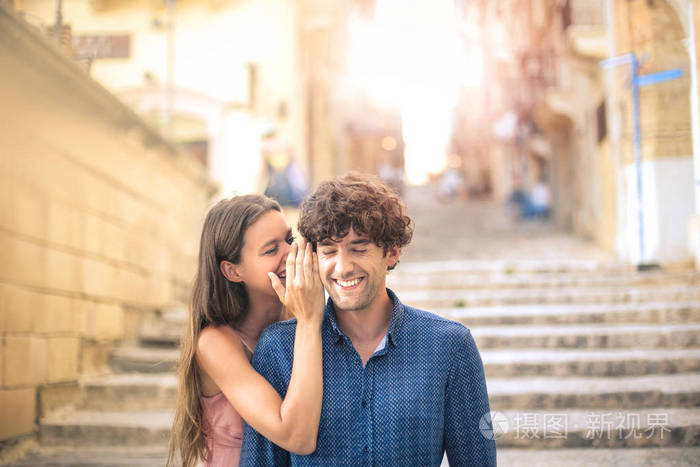 女孩耳语在男孩的耳朵