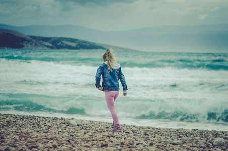 孤独的女孩，在恶劣的天气在海边散步，